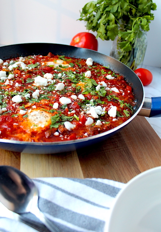 Gorgeous red spicy Shakshuka with Chorizo Sausage topped with feta cheese, fresh parsley, and delicately poached eggs.