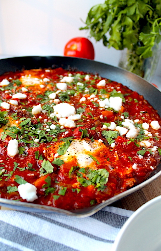 Peeking into the skillet to see the delicately poached eggs, beautiful red tomatoes, fresh green herbs and crumbly white cheese.