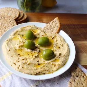 Beautiful Mediterranean Hummus, topped with bright green castelvetrano olives, and drizzled with olive oil.