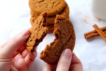 Breaking open a molasses cookie to show the chewy inside.