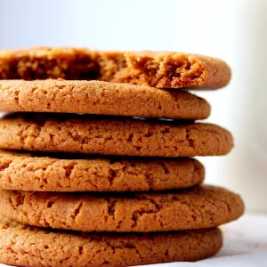 Chewy, ginger spiced, molasses cookies with a crinkle top, stacked with a broken cookie on top to show the beautiful texture inside.