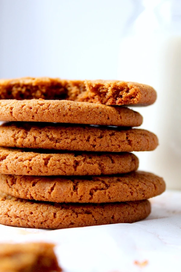 Chewy, ginger spiced, molasses cookies with a crinkle top, stacked with a broken cookie on top to show the beautiful texture inside.