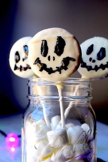 Adorable Nightmare Before Christmas Cookie Pops peeking out of a mason jar filled with marshmallows.