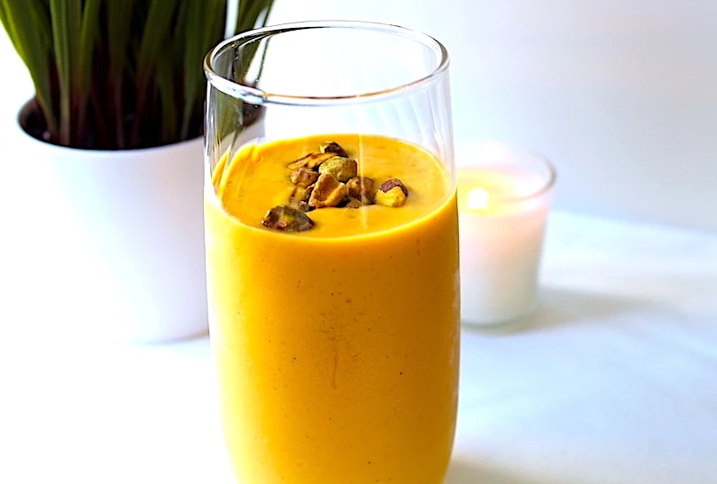 Peering into the glass filled with bright orange Cardamom Spiced Mango Lassi