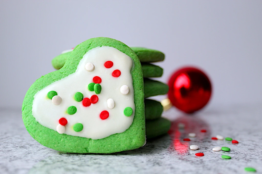 Green Grinch Inspired Almond Sugar Cookies with cute Christmas sprinkles and sugar cookie icing.