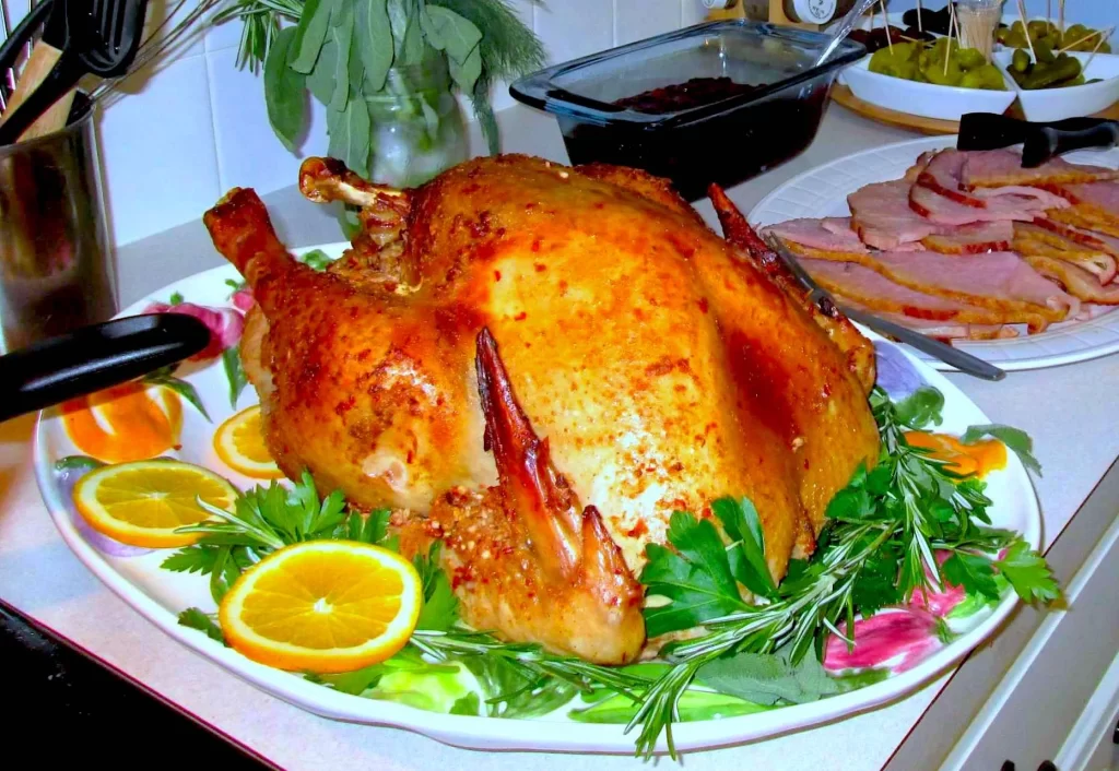 A Turkey that has been roasted in Portuguese marinade. Surrounded by orange slices and fresh herbs.