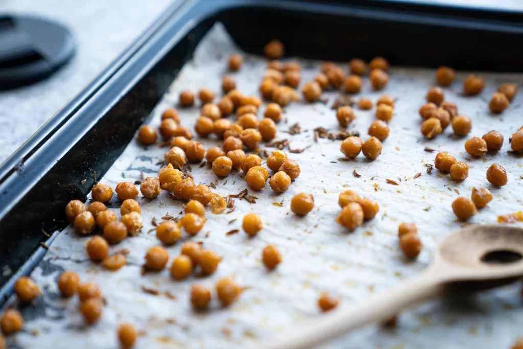 A sheet pan covered in recently roasted chickpeas is shown.