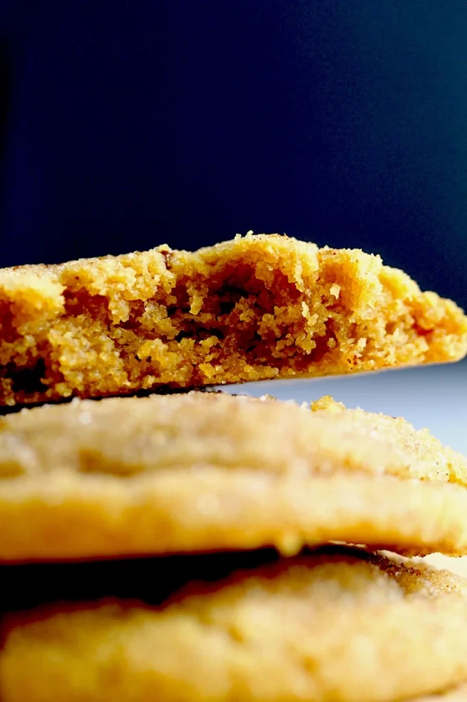 A slice is cut to reveal the center of a soft, chewy and delicious spiced brown butter pumpkin-doodle cookie.