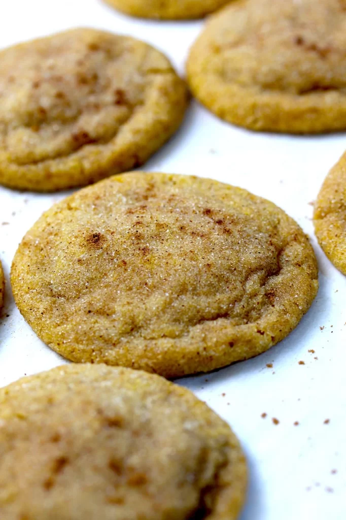 Lined on a baking tray, covered with parchment paper are beautiful cookies covered in specks of pumpkin spice and ground ginger.